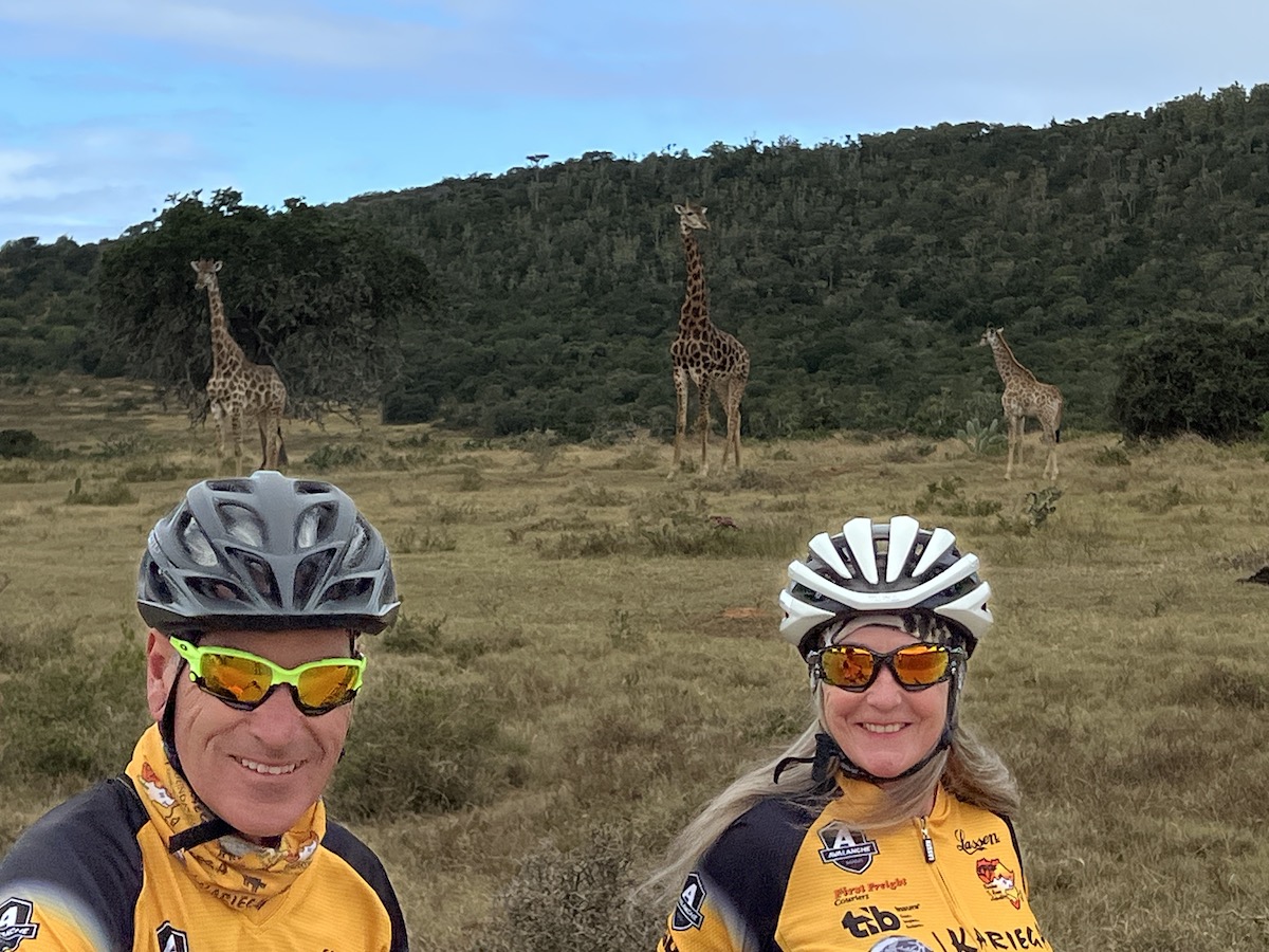 Scott and Jacinta cycling with giraffe at Kariega